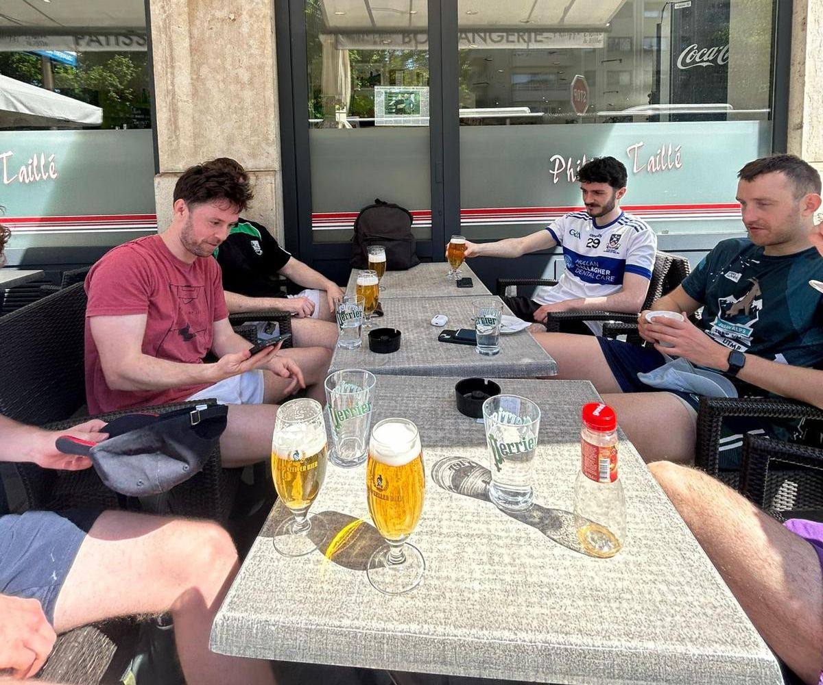 Players sitting at a café terrace table with glasses of beer