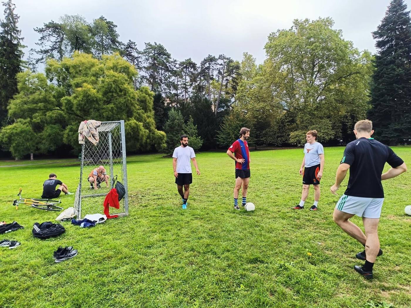 Gaels players at training on a park pitch, standing around a goal on a sunny evening
